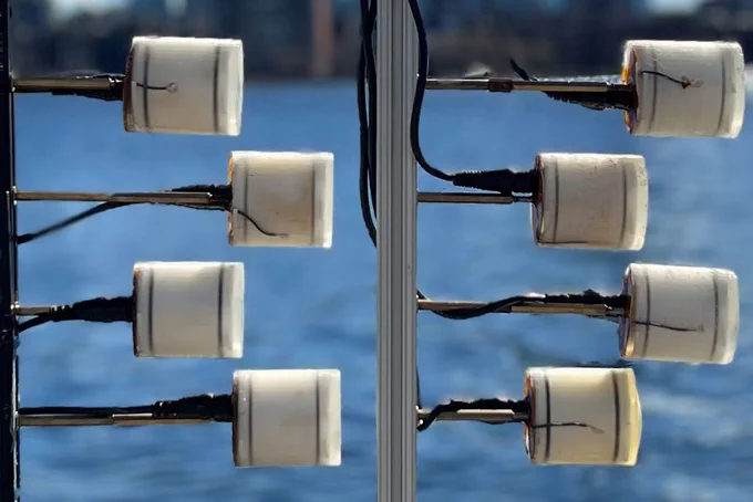 8 piezoelectric transducers look like toilet paper rolls and are attached to poles, near water.