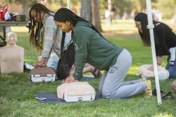 Three students practicing CPR on UCDFD equipment.