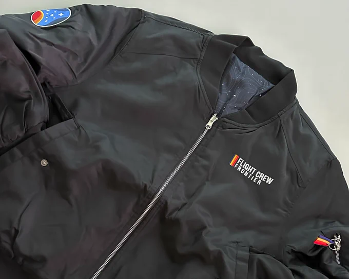 A black bomber jacket with the words "Flight Crew Frontier" on the chest and a Constellation patch on the shoulder
