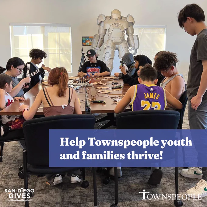 White text highlighted by a transparent light blue rectangle, layered over a daytime color photos of children, young teens, and older teens seated around a dark brown conference table in a carpeted and well-lit meeting room. The children and teens are in the middle of a cardboard making craft. White text says, "Help Townspeople youth and families thrive!" White San Diego Gives logo in the bottom left corner of the graphic. White Townspeople logo in the bottom right corner of the graphic.