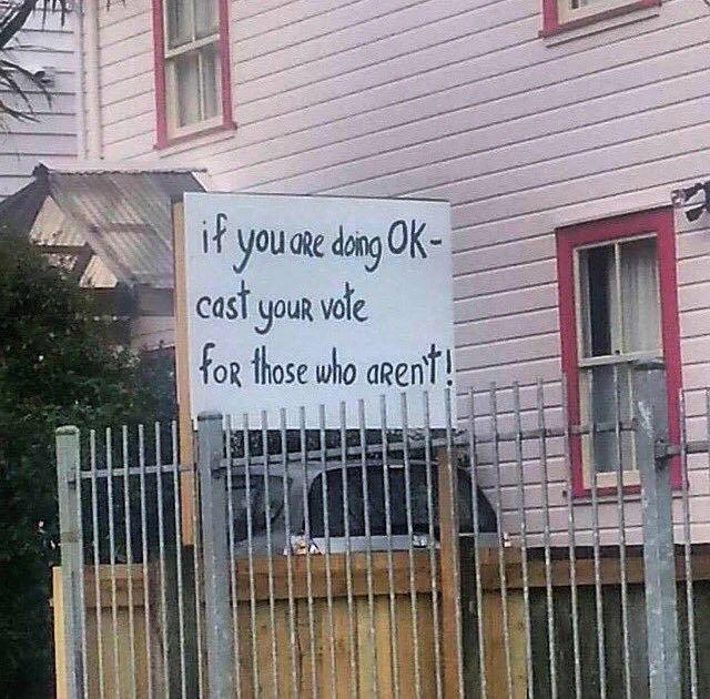 Handmade sign outside a house saying "If you are doing OK - cast your vote for those who aren't!"