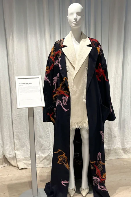 A mannequin models a black, embroidered coat.