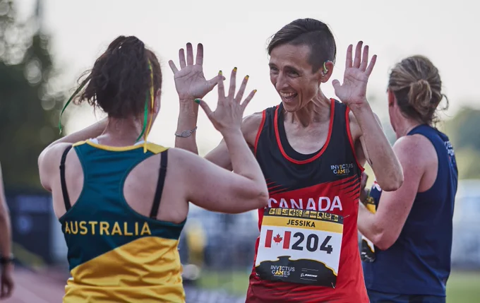 Two runners high five each other.