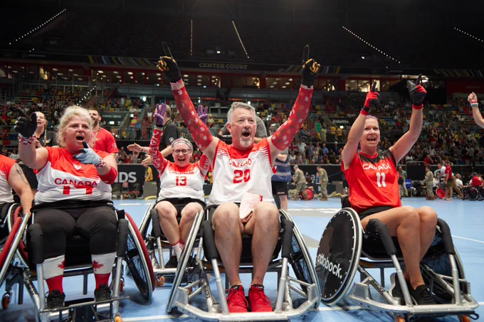 Athletes in wheelchairs cheer on in the stadium.