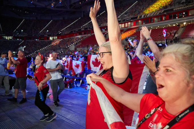 A crowd adorning Canadian flags cheer on in a stadium.