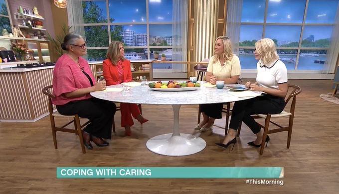 Emily Holzhausen OBE sits around a table with Kate Garraway and the This Morning Hosts on set of ITV