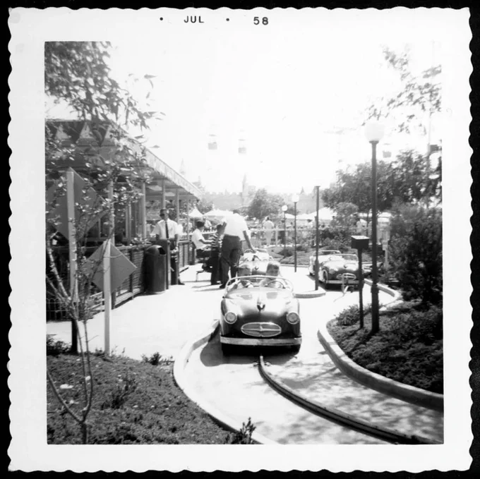 Black and white photo of Disneyland's Midget Autopia attraction in 1958. Small cars that move around a railed track.