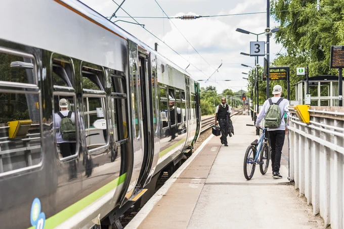 Train at a platform with a passenger walking with their bike