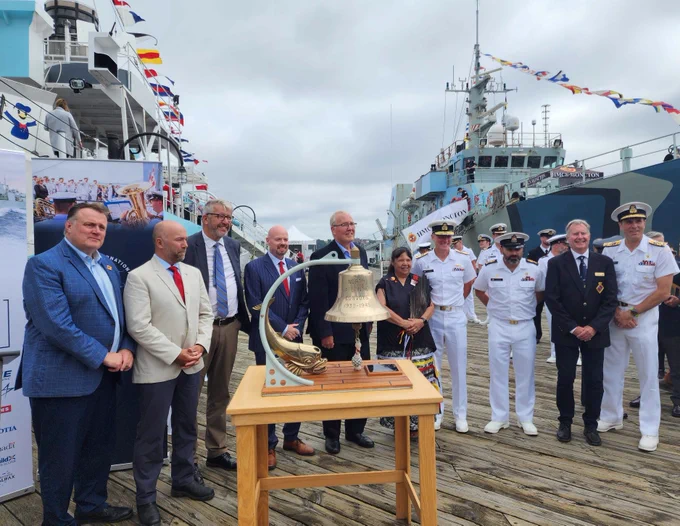 a group of politicians and navy folks gathered around a bell on the jetty of HMCS Sackville