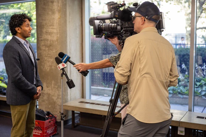 Kevin inside Toronto City Hall being interviewed on camera by CBC News and CityNews crews