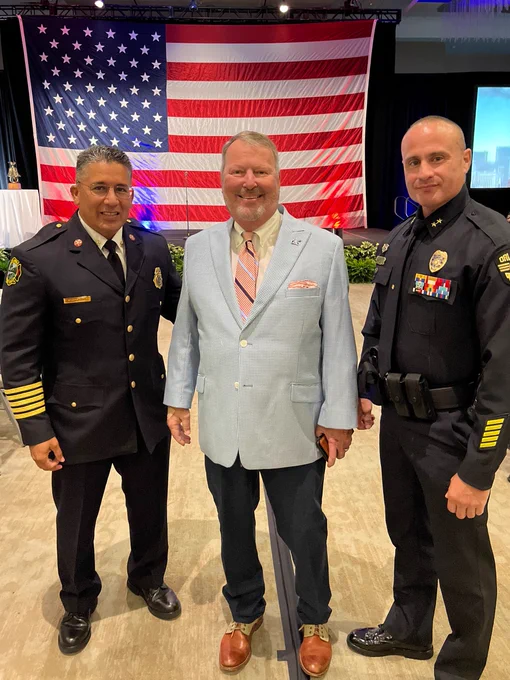In front of a U.S. flag, Mayor Dyer stands with OFD Chief Salazar and OPD Deputy Chief Caro.