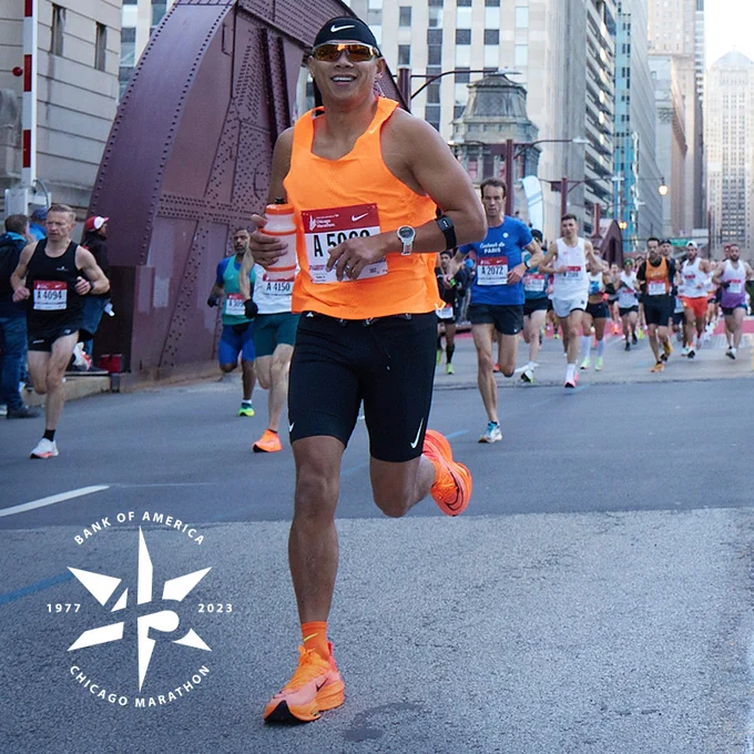A marathon participant smiles to camera while running the Chicago Marathon.