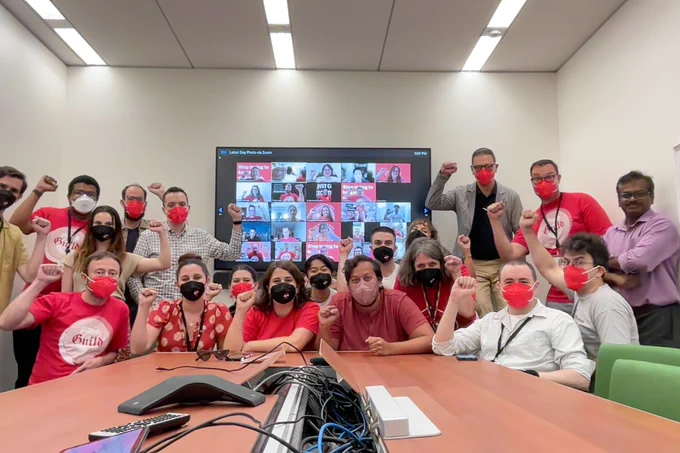 Group of in person and virtual union members raising fists in solidarity.