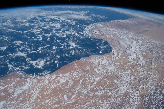 The Expedition 43 crew on the International Space Station took this photo of North Africa while passing overhead. Land and water each take up about half of the image; blue water hugs the curvy land border. White clouds appear over water and land, and at the very top of the image, the darkness of space can be seen. Credit: NASA