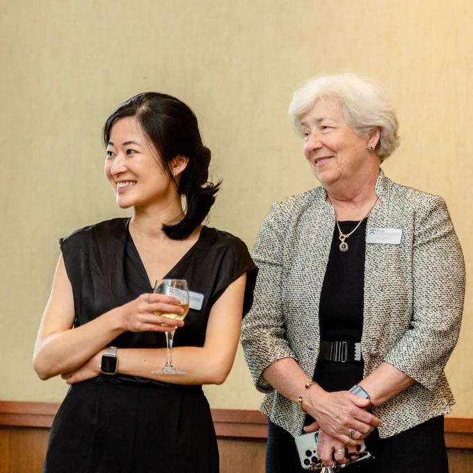 A faculty member and SP2 Dean Sara Bachman stand side by side indoors smiling.
