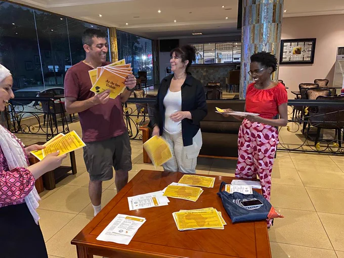 Four people standing and laughing and holding cards