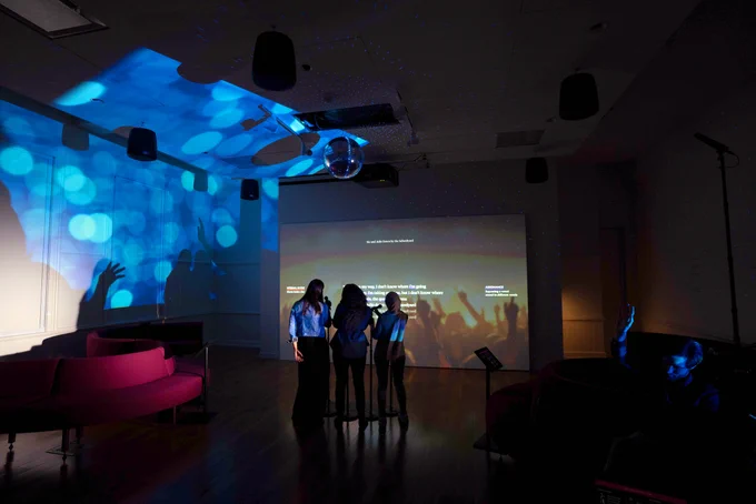 Three women singing into microphones with their backs to the camera in the Unlock the Music gallery at Planet Word.