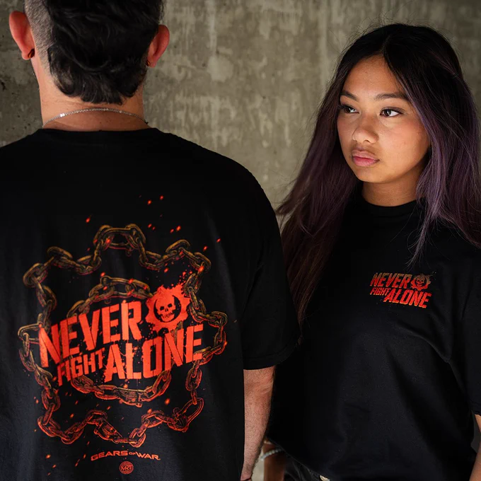 Two people wearing black t-shirts with the Never Fight Alone logo on the back. 