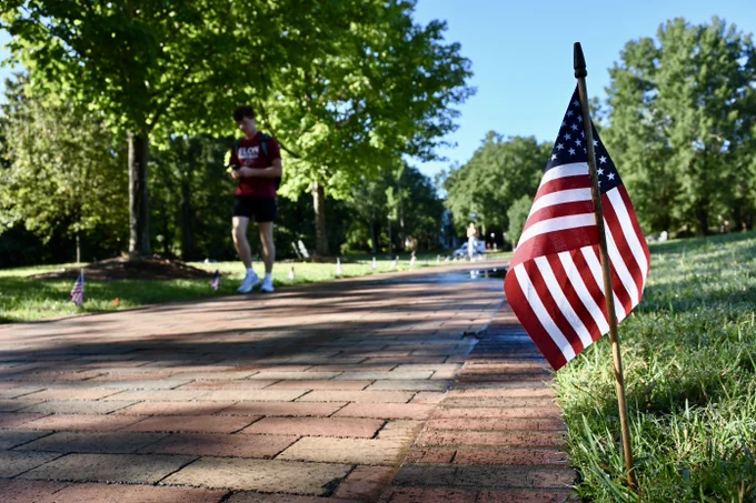 A student walks on Young Commons, which is lined by mini American flags.