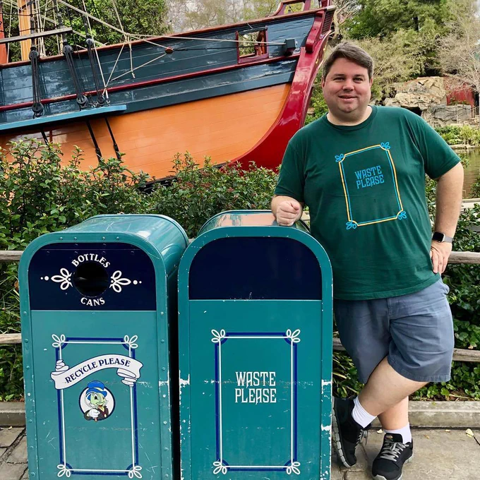 Man standing next to Haunted Mansion-style trash cans wearing a matching shirt