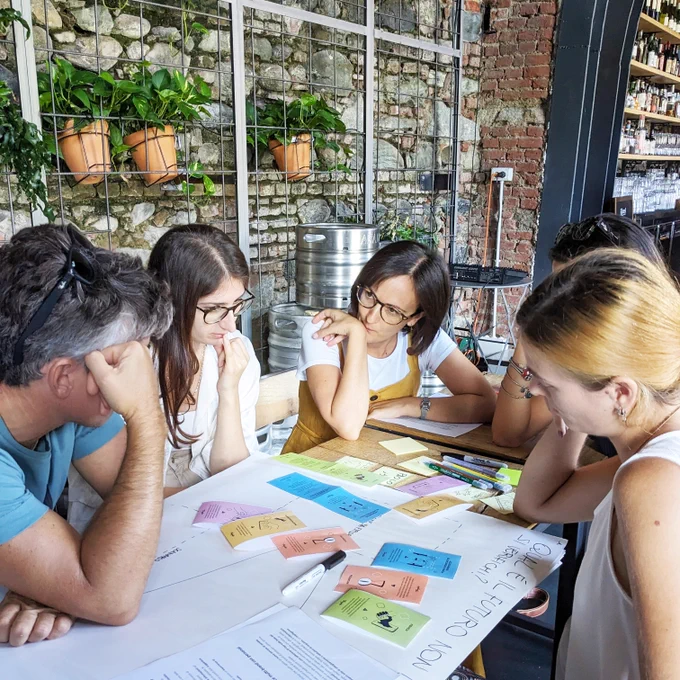 Un gruppo di persone sedute intorno a un tavolo con dei post-it adesivi.