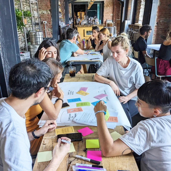 Un gruppo di persone sedute intorno a un tavolo con dei post-it adesivi.
