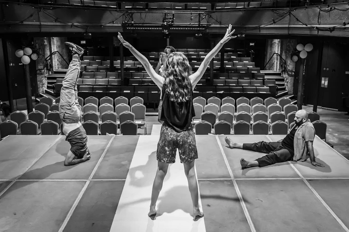 Three actors stretch on stage