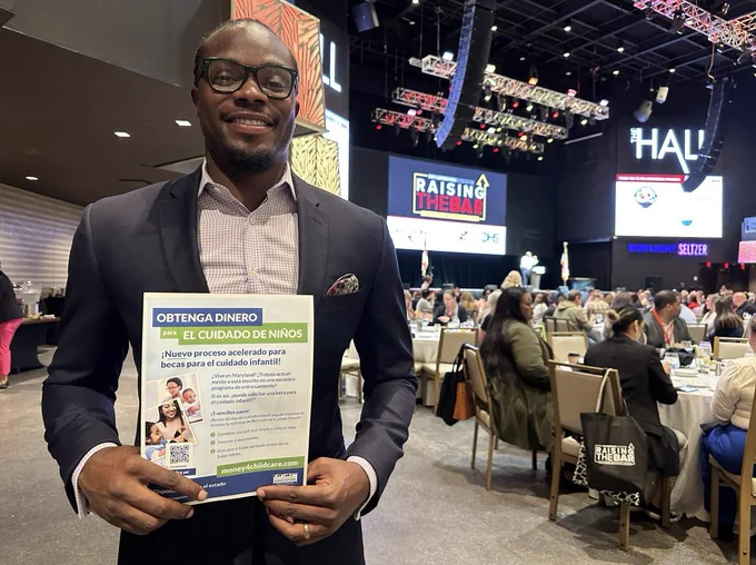 State Senator Alonzo T. Washington holding the Spanish fast-track Child Care Scholarship application process flyer at the Raising the Bar Conference.