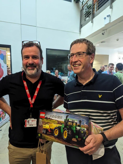Outgoing director Chris Scott holding a Lego Technic tractor with new Director Dan Longley