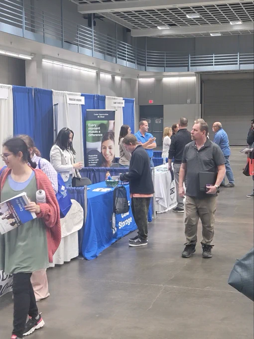 A crowd of people walk by a line of employer booths during the St. Cloud Area Career Fair. 