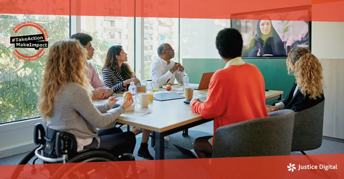 Colleagues in a meeting, sitting around a table watching a video on a TV screen. 