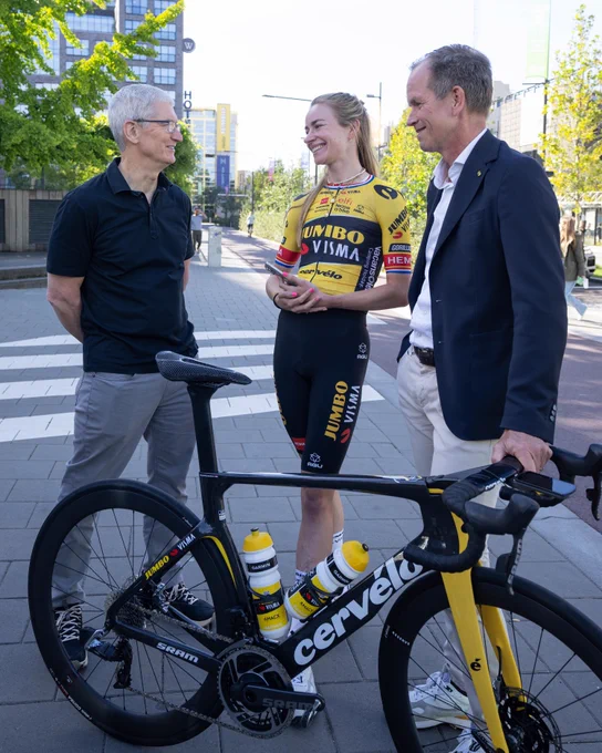 Tim speaks with Riejanne Markus and Richard Plugge on the street next to a bicycle.