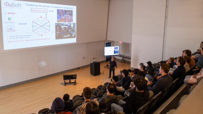 Harry Buhrman at the front of a lecture room filled with an attentive audience