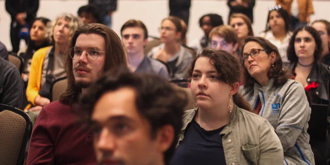Several rows of people sitting and listening attentively.