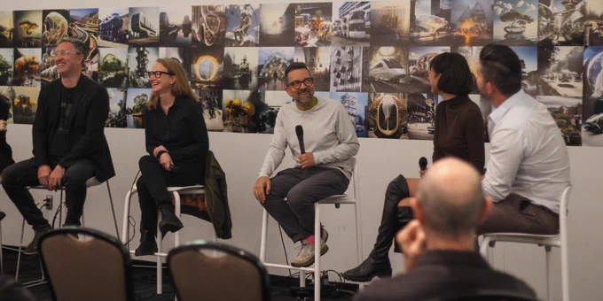 Five panelists sitting on benches, laughing and conversing.