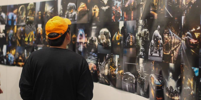 A person examining various printed designs mounted on a wall.