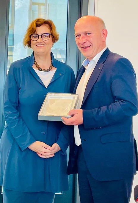 Gesundheitssenatorin Dr. Ina Czyborra steht neben dem Regierenden Bürgermeister Kai Wegner, der den Preis in der Hand hält.  