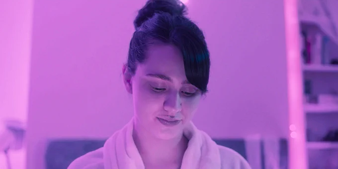 A young woman hangs out in her bedroom in a scene from WHOLE
