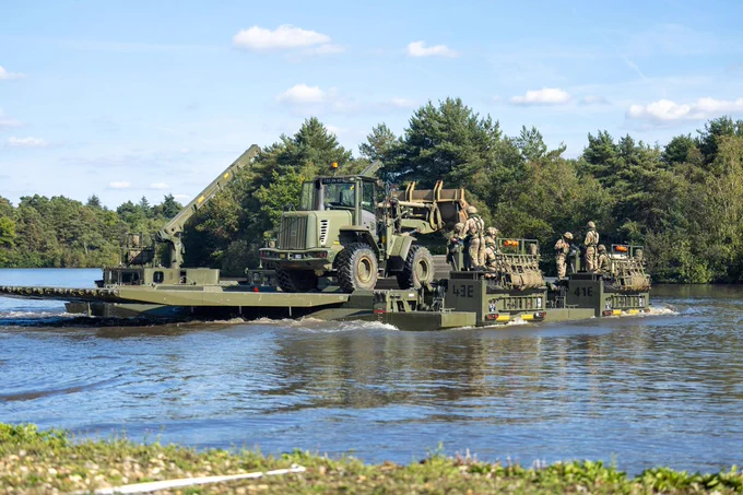 A tractor crosses a river on a bridge built by the Royal Engineers.