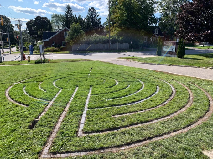 A circular labyrinth, made of paving stones set into a lawn, is being built. The area to the right is more developed, with the back and left needing more work.