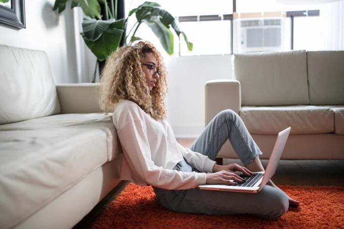 Girl on the floor with a laptop on her laptop typing