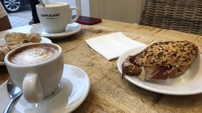 Mesa de cafetería con dos cafés, pulga de jamón y palmeritas de leche merengada