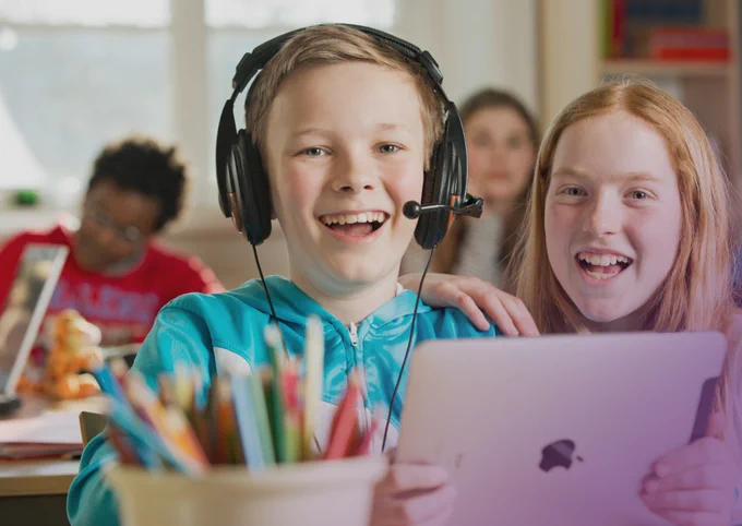 Två skolbarn med dator i ett klassrum.