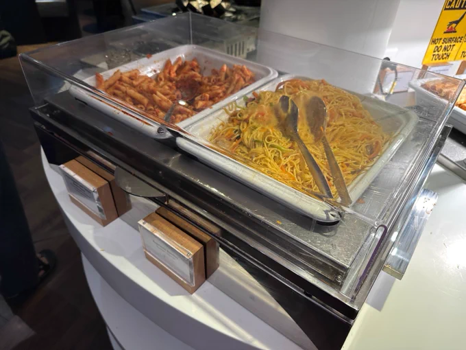 Unappetizing-looking pasta dishes on hot plates in the lounge.