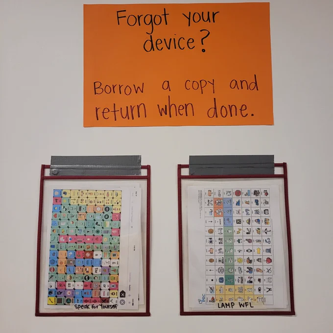 A poster that says, “forgot your device? Borrow a copy and return when done” underneath the poster are two pocket folders. One with speak for yourself core boards and one with LAMP core boards.