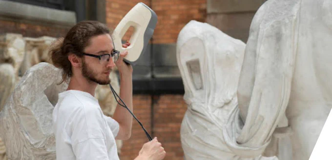 A photo depicting a person 3 D scanning a sculpture. 