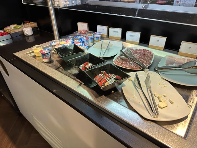 The cold section of the buffet with picked over meats and cheese plates.