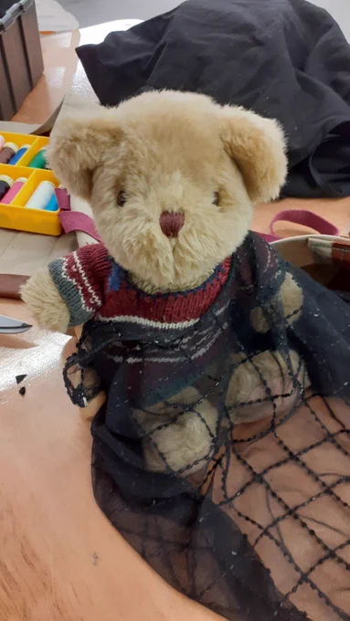 Repair Bear is draped in a black net scarf. 