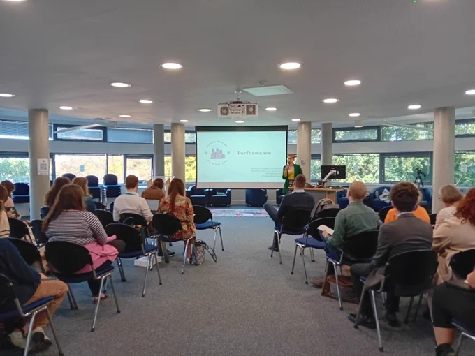 A lecture room full of people. The screen at the front of the room says ‘Performance’.