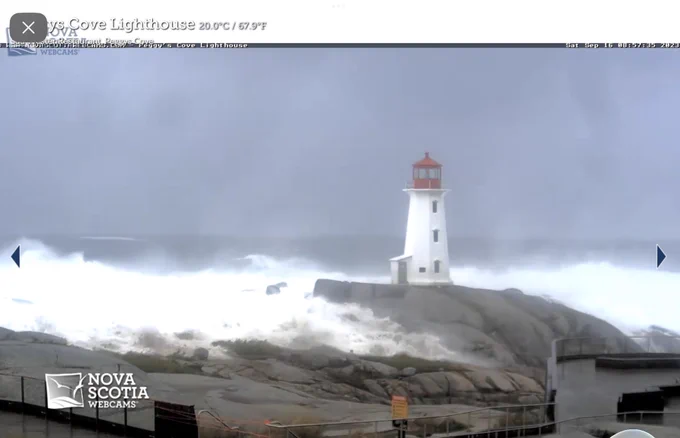 Screen grab of Peggy’s Cove webcam shows the rocks covered in water on the camera side of the lighthouse. Huge waves in the background beyond the lighthouse.